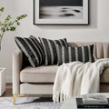 Luxurious Waterman Pillows displayed on a beige sofa, featuring elegant black and white stripes, enhancing a modern living room decor.