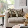Pair of Luxurious Landino Pillows on a beige sofa next to a wooden side table, showcasing the intricate woven design with earthy tones. Enhances the aesthetic appeal of any living room setting.